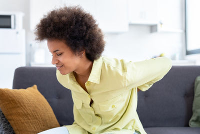 Side view of young woman using mobile phone at home