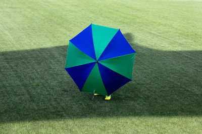 Low section of child with umbrella on playing field