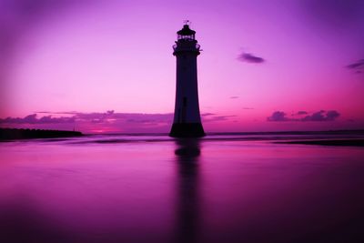 Lighthouse at beach during sunset