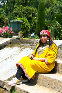 Portrait of young woman sitting on footpath