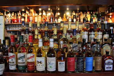 Various bottles on shelf at bar counter