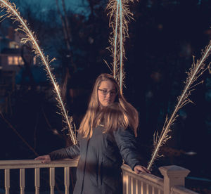 Young woman with arms raised at night