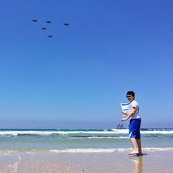 Full length of boy holding israeli flag at beach