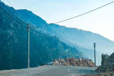 Electricity pylon by road against sky