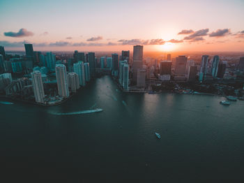 Aerial view of city buildings against sky during sunset