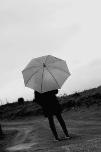 Rear view of a man holding umbrella
