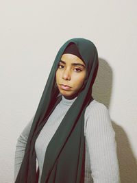 Portrait of young woman standing against wall