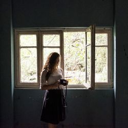 Rear view of girl looking in front of window