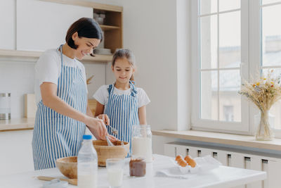 Mother with daughter preparing food in kitchen