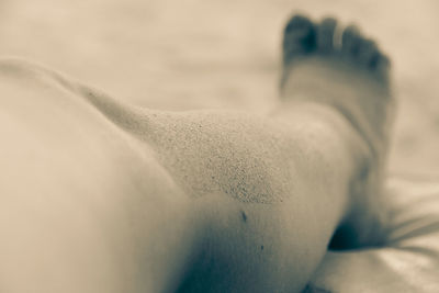 Low section of person lying on sand