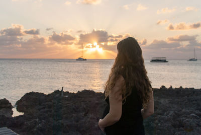 Man looking at sea against sky during sunset