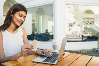 Young woman using phone while sitting on table