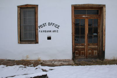 Text on snow covered house against building