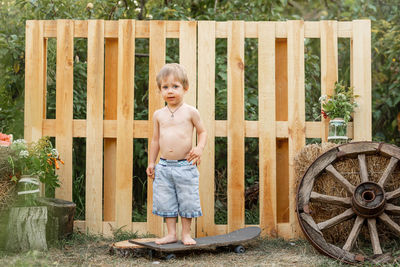 Portrait of shirtless boy standing on wood