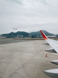 Airplane flying over airport runway against sky