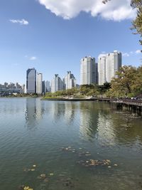 River by modern buildings against sky in city