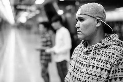 Man wearing cap looking away at subway station