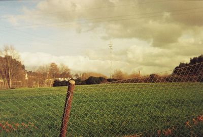 Scenic view of grassy field against cloudy sky