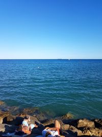 Low section of woman on beach against clear blue sky