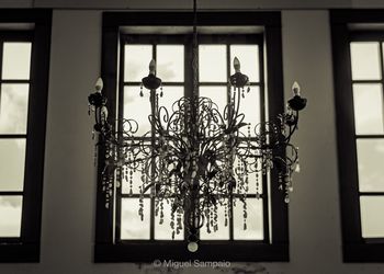 Low angle view of illuminated chandelier hanging on ceiling