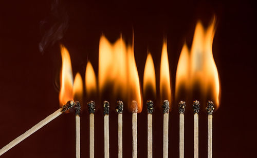 Close-up of burning candles against black background