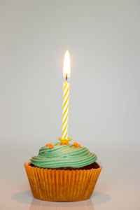 Close-up of lit tea light candle against white background