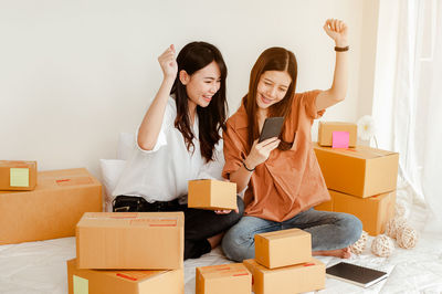 Young woman using phone while sitting in box