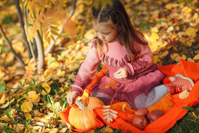 Full length of girl holding autumn leaves