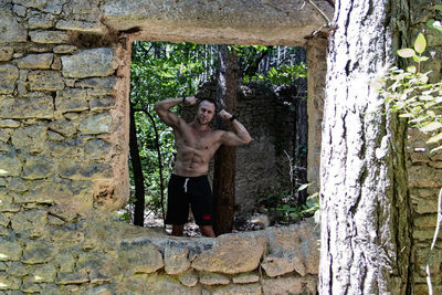 Full length of shirtless man standing against wall