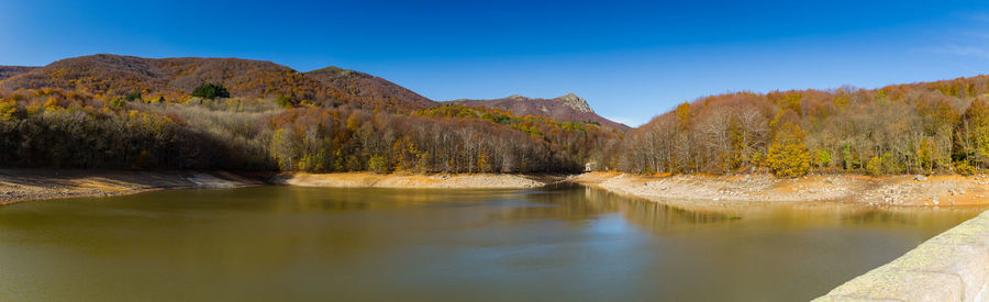 Scenic view of lake and mountains against blue sky
