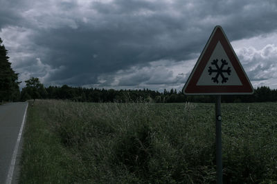 Road sign on field against sky