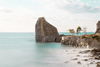 Rock formation in sea against sky