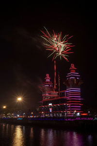 Firework display in city against sky at night