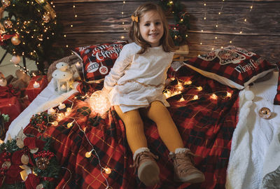 Little four year girl in living room decorated by christmas tree and present gift box