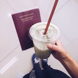 Cropped image of hand holding smoothie and passport