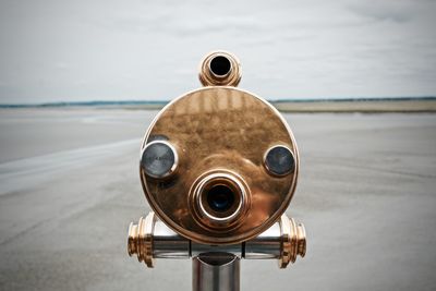 Close-up of coin-operated binoculars at beach against sky