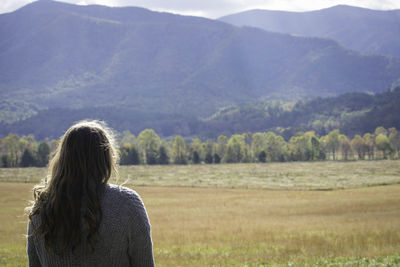 Rear view of woman on field against mountains