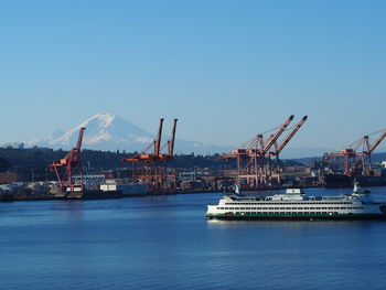Ships moored by harbor at sea with mount rainier in background