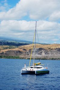 Boats sailing in sea against cloudy sky