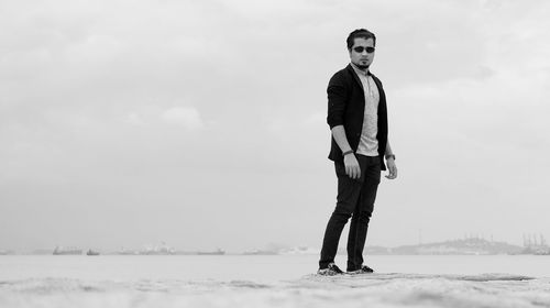 Man standing on snow covered shore against sky