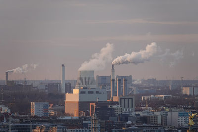 Smoke emitting from factory against sky