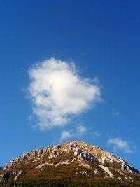 Low angle view of rocky mountain against blue sky