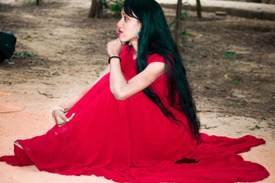 Midsection of woman with red umbrella on land