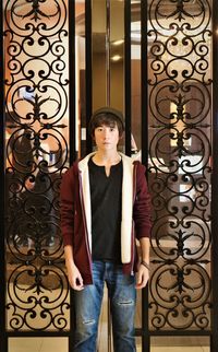 Portrait of teenage boy standing against wrought iron