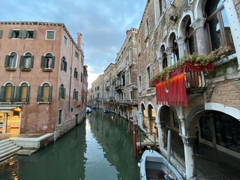 Canal amidst buildings in city against sky