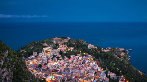 High angle view of townscape by sea against blue sky