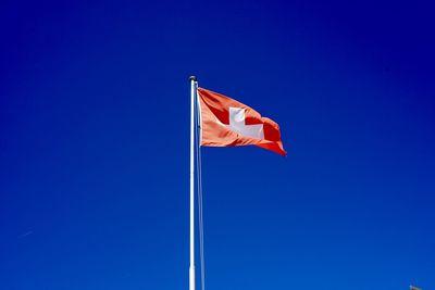 Low angle view of flag against blue sky