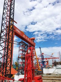Low angle view of cranes at harbor against sky