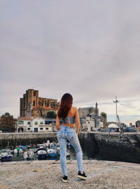 Rear view of woman standing by cityscape against sky