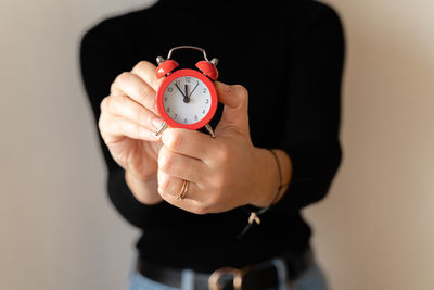 Woman's hands holds red alarm clock. businesswoman adjusting or changing the time on vintage clock.